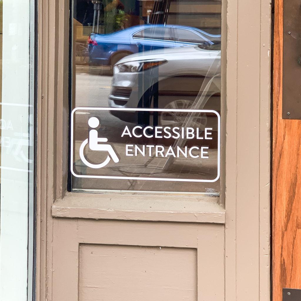 Picture of the Accessible Entrance label on A2AC's front door. 